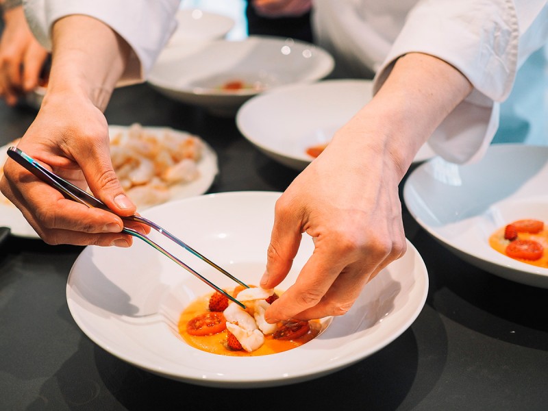 Cocinero profesional preparando un plato en un restaurante con estrella michelin